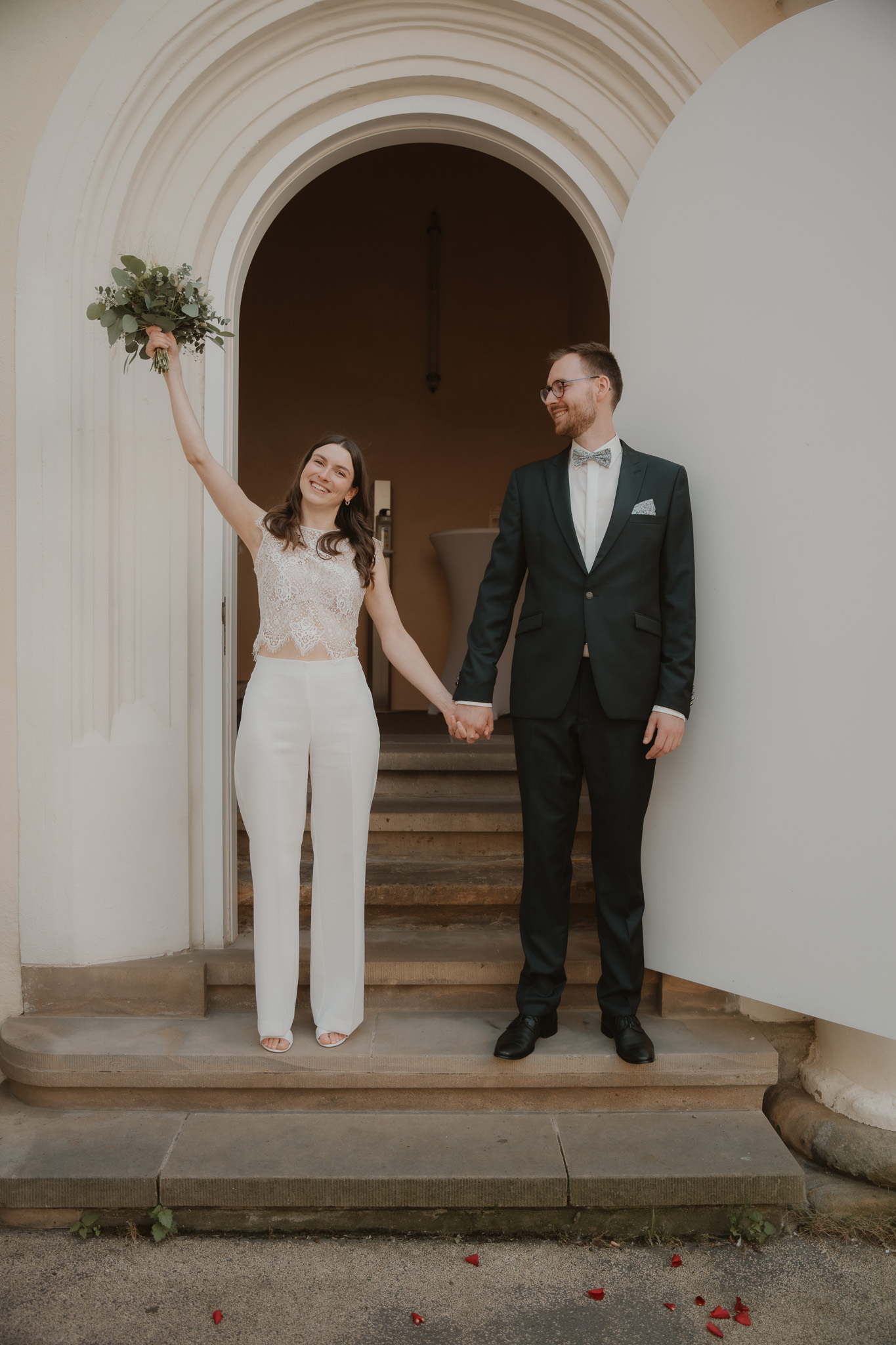 Brautpaar jubelt mit Blumenstrauß vor Tor